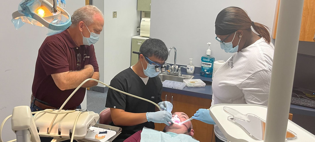 Picture of Dr. Justin Le inserting the final restoration. Tony Cirigliano of The Dental Lab on the left watches. Shanika Mosley assists Dr. Le on the right.